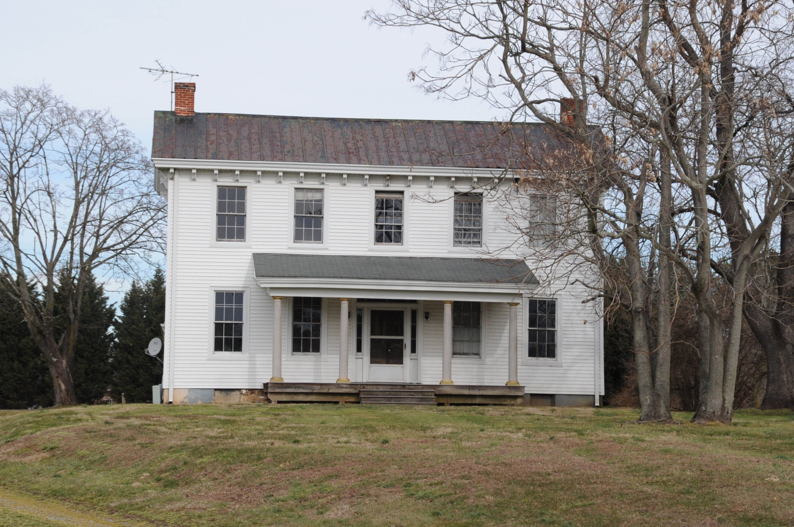 JERRYE & ROY KLOTZ, M.D., CC BY-SA 4.0 , via Wikimedia Commons A historical white house known as White Hall located in Bear, Northern New Castle County, Delaware. The house features a classic architectural style with a simple rectangular shape, multiple windows, a central front door, and a small porch supported by four columns. The roof has a weathered appearance, and the surrounding landscape includes bare trees, suggesting a winter season. The house stands on a slightly elevated grassy area.
