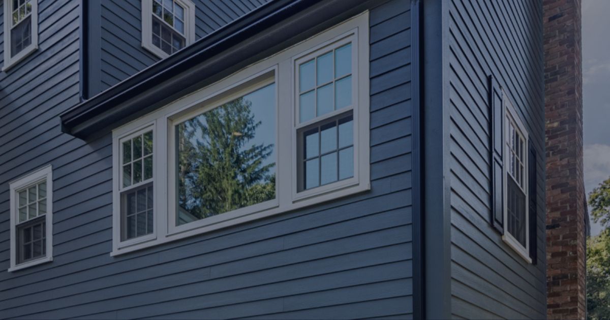 Close-up view of a home with James Hardie fiber cement siding installed, showcasing durable and stylish blue siding with white-trimmed windows. Ideal for enhancing curb appeal and weather resistance in homes across Berlin, MD.